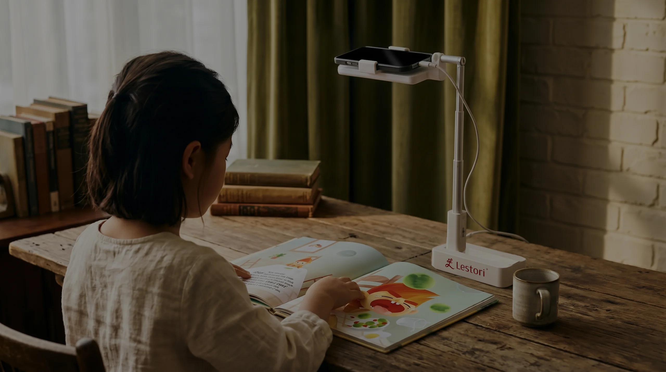 A child reads a picture book under a phone on a Lestori stand
