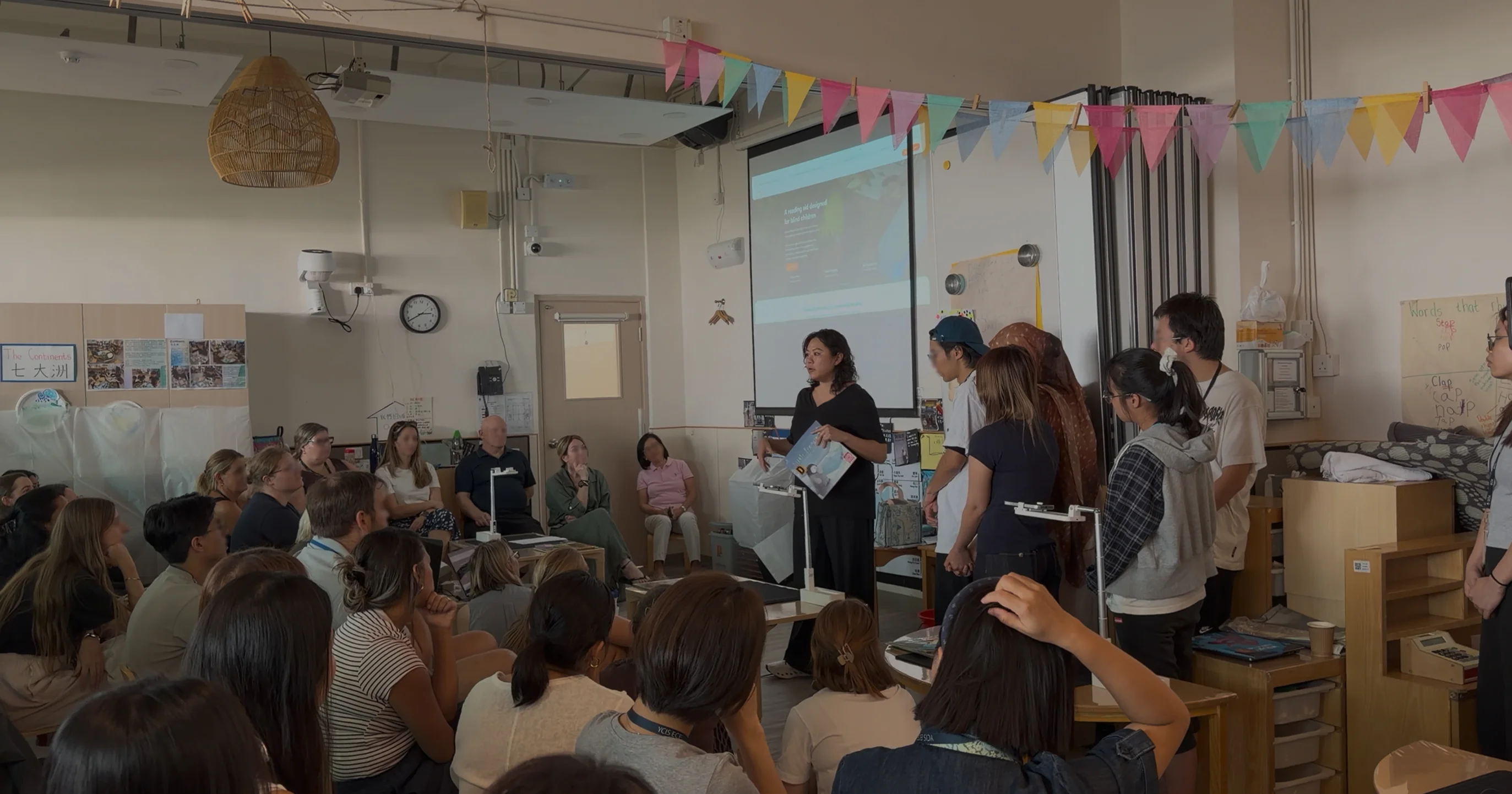 A presenter shows a book and a Lestori stand to a classroom group